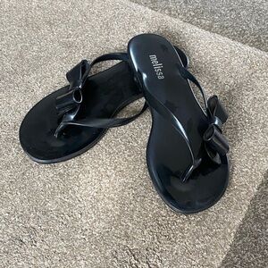 This is a pair of black Melissa Harmonic Eclipse flip-flops made of PVC